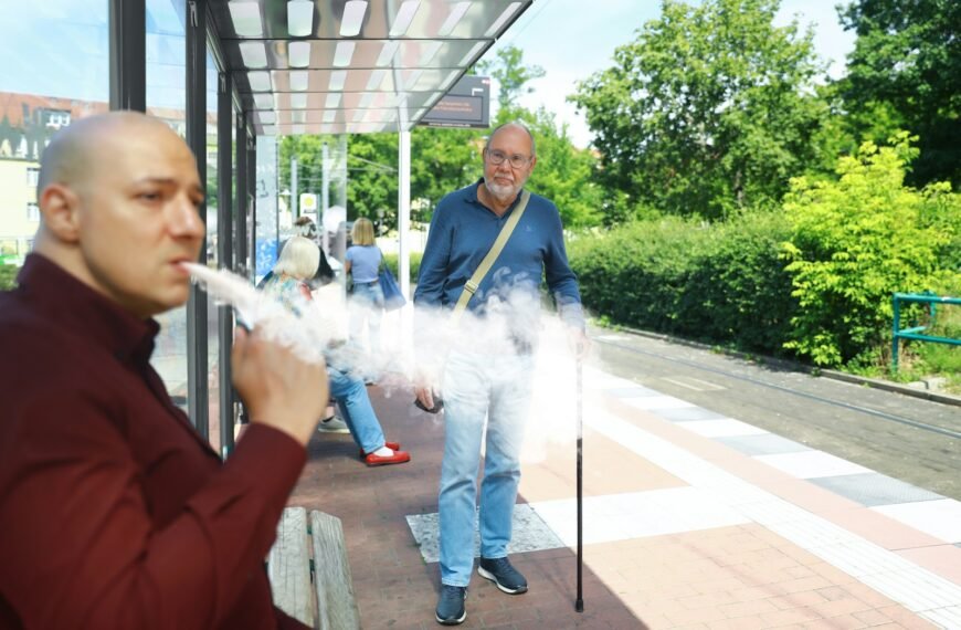 a man smoking a cigarette in front of a bus stop