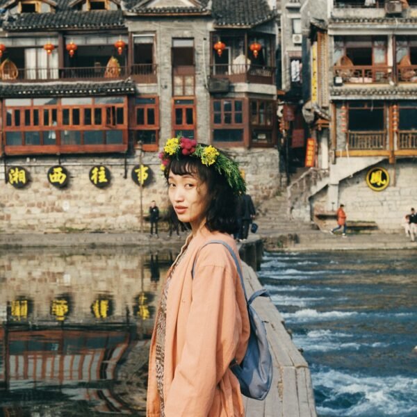 woman in pink dress standing in front of lake near temples