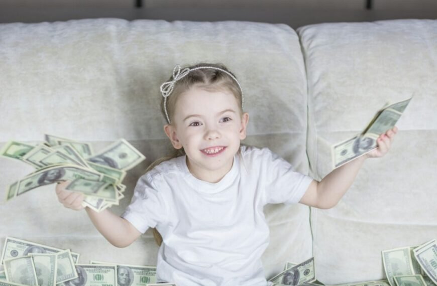 a little girl sitting on a couch holding money