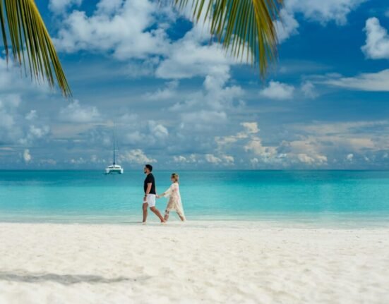 couple walking on beach during daytime