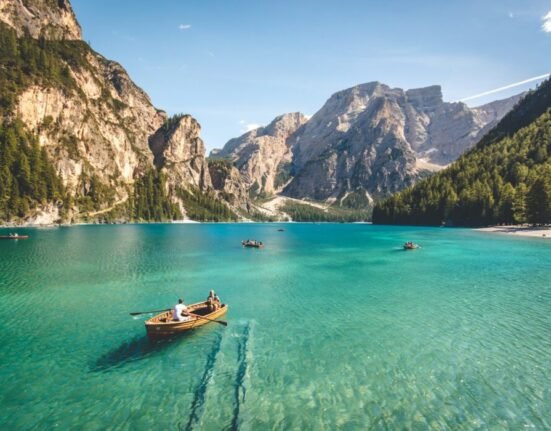 three brown wooden boat on blue lake water taken at daytime