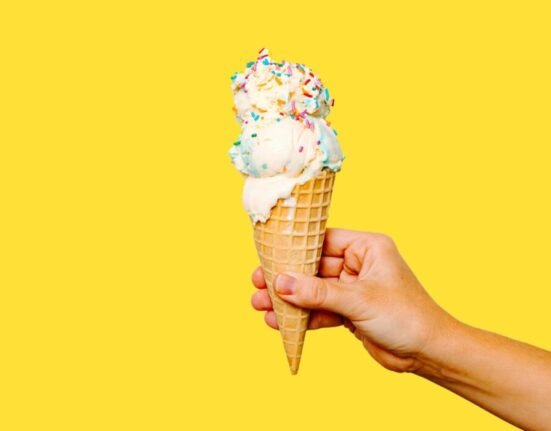 A hand holding an ice cream cone with sprinkles