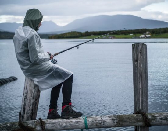 man in white jacket fishing on sea during daytime