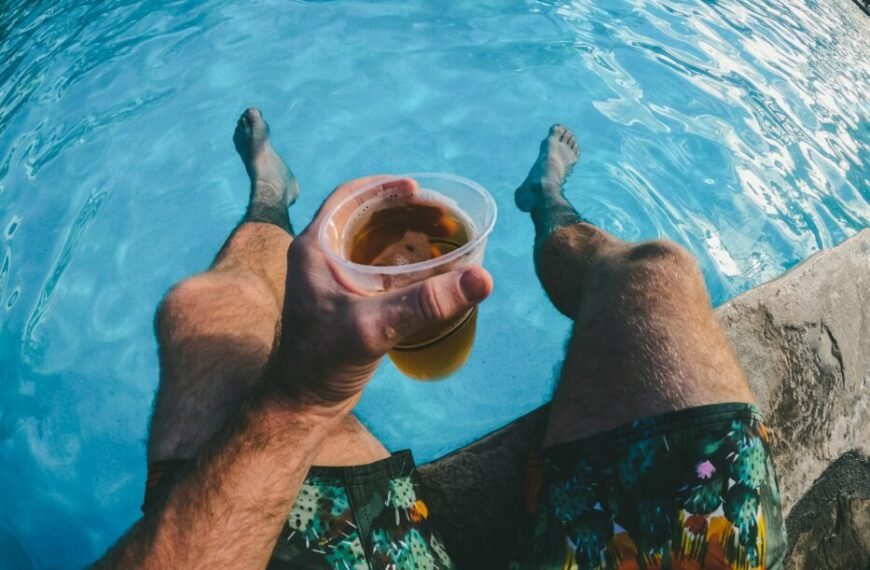 man holding a cup of drink while dipped in the swimming pool