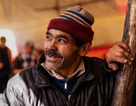 man in black leather jacket wearing red and white knit cap