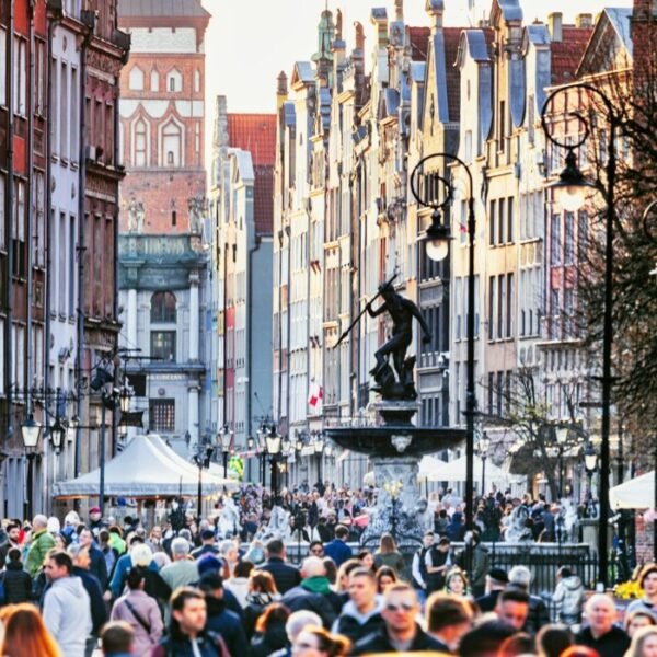 a crowd of people walking down a street next to tall buildings