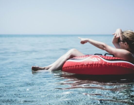 Woman on an inflatable float in the ocean pointing with a finger at Posidi