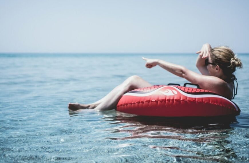 Woman on an inflatable float in the ocean pointing with a finger at Posidi