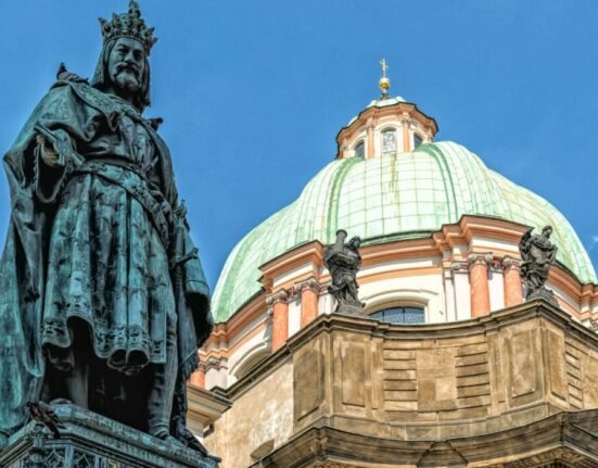 a statue stands in front of a domed building